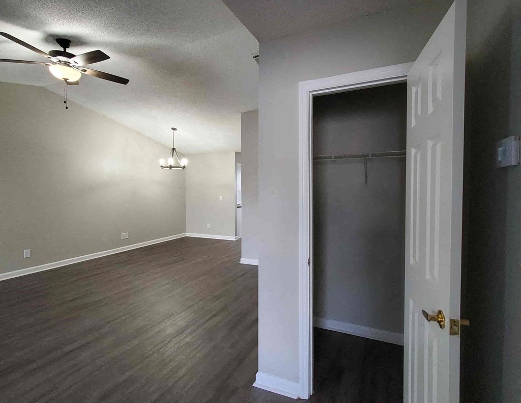 an empty living room with a closet and a ceiling fan