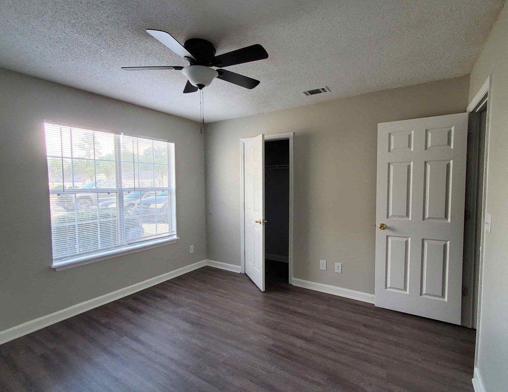 an empty living room with a ceiling fan and a window