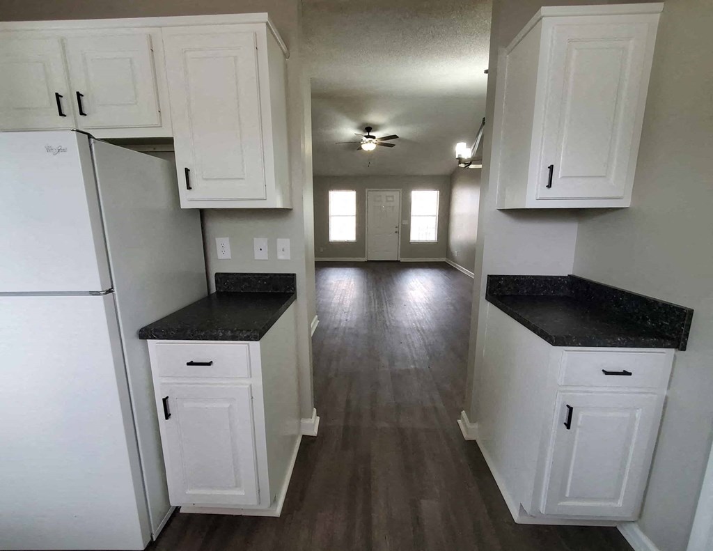 a kitchen with white cabinets and black counter tops