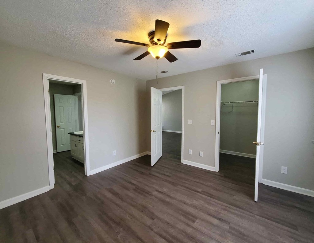an empty living room with a ceiling fan and a closet