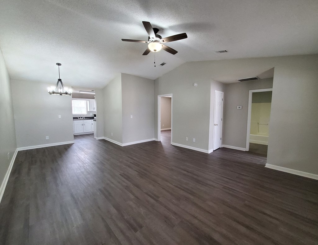 an empty living room with wooden floors and a ceiling fan