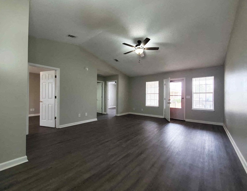 an empty living room with a ceiling fan