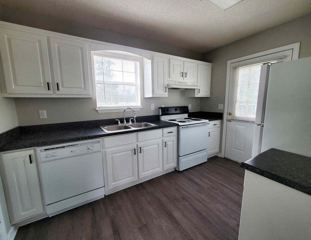a kitchen with white cabinets and a sink and a refrigerator