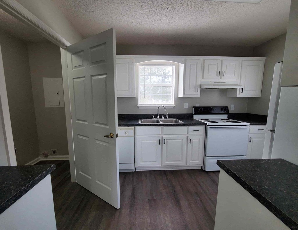 a kitchen with white cabinets and a sink and a window