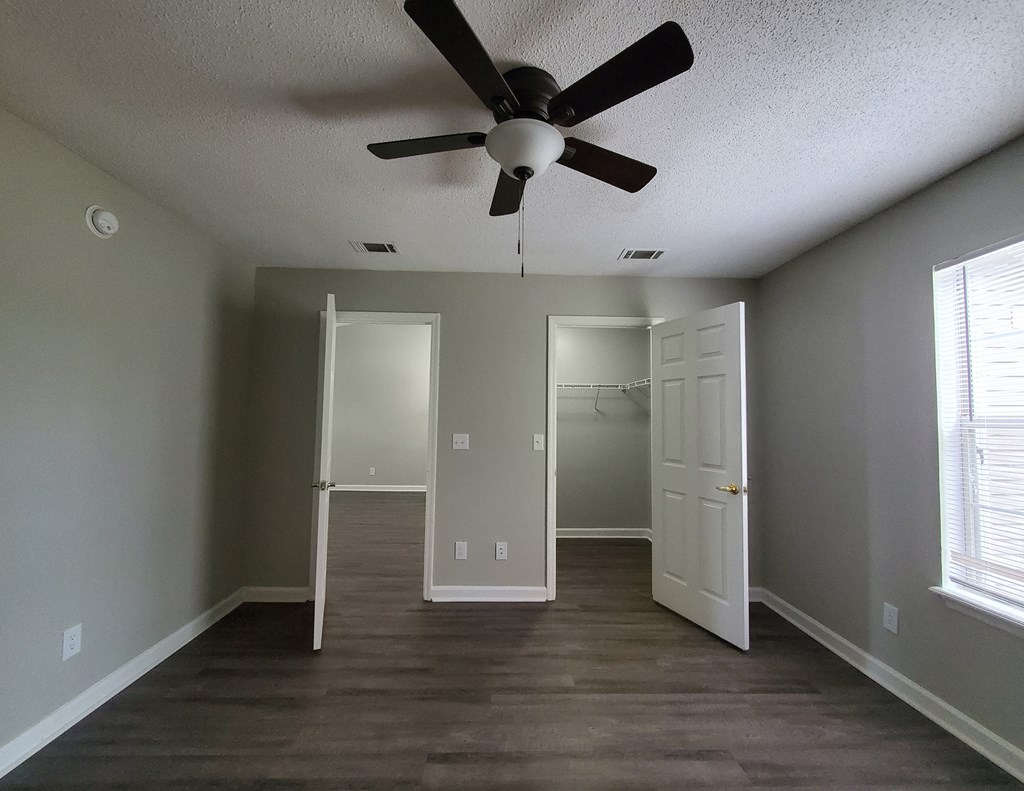 an empty living room with a ceiling fan and a closet
