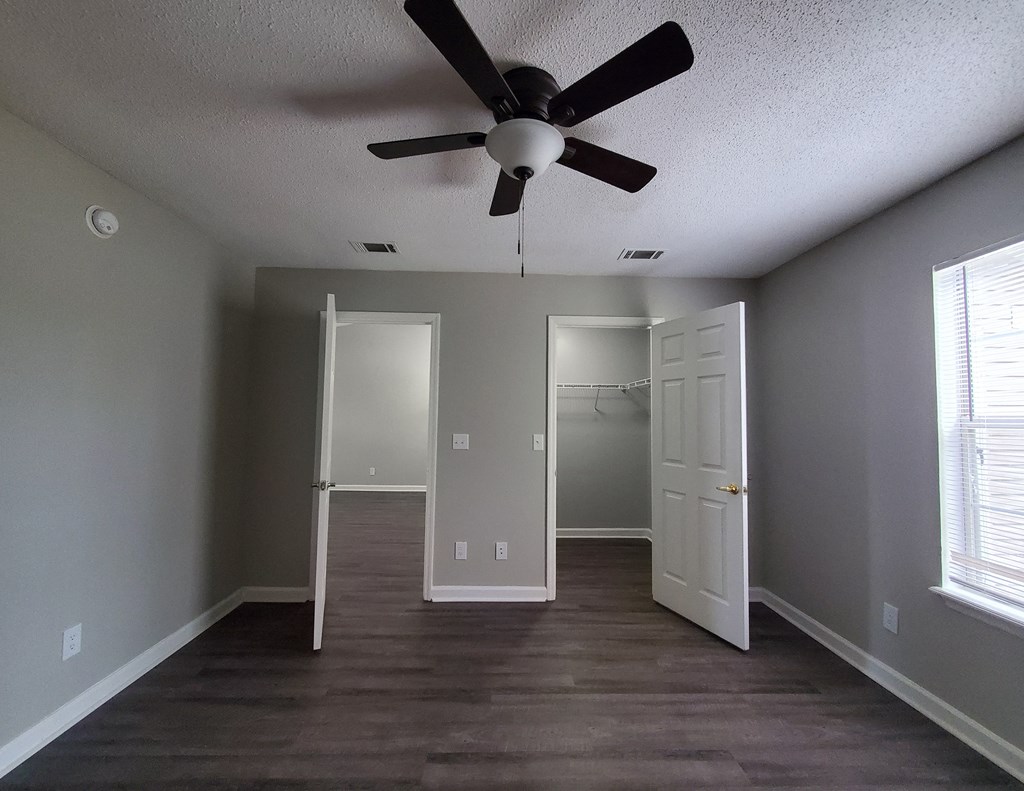 an empty living room with a ceiling fan and a closet