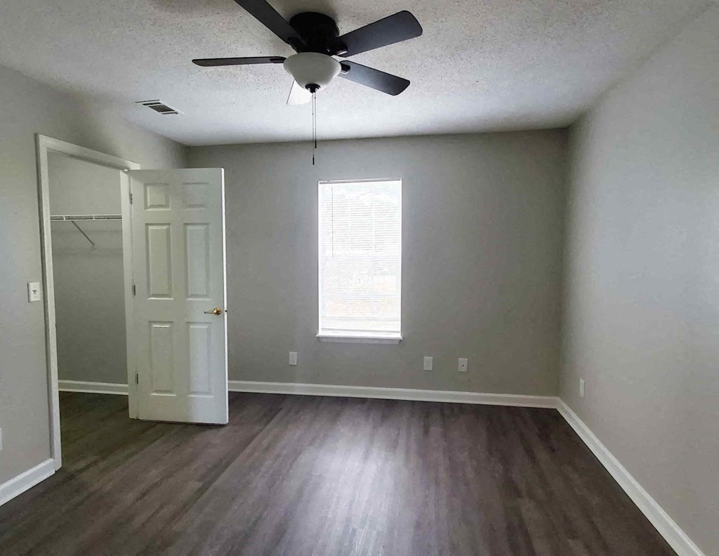an empty living room with wood floors and a ceiling fan