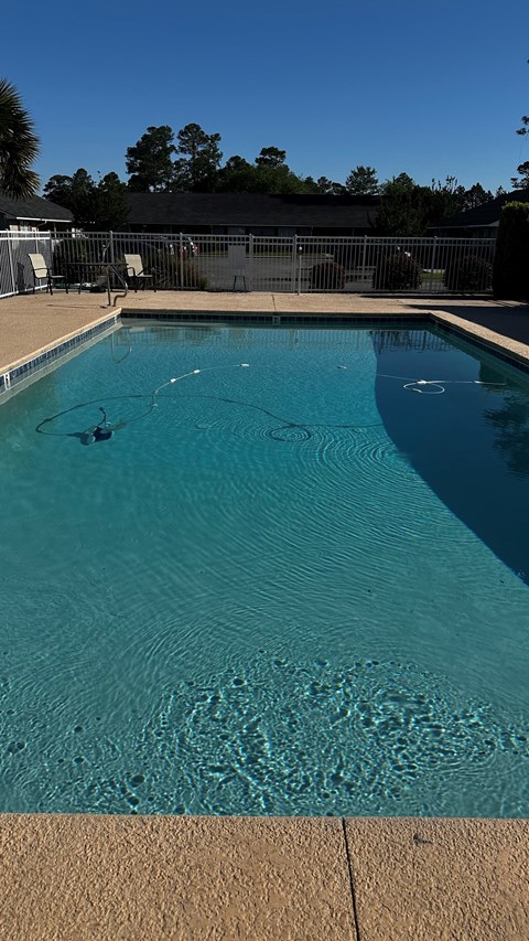 A swimming pool with a clear blue water and a brownish floor.