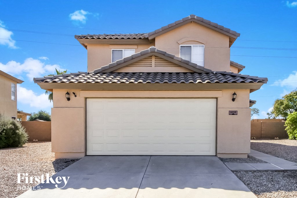 A house with a garage door in the foreground and a clear blue sky above.