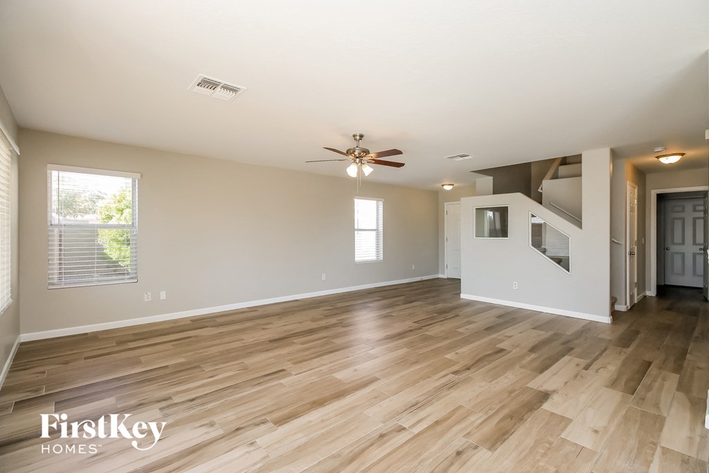 A spacious room with wooden flooring and a ceiling fan.