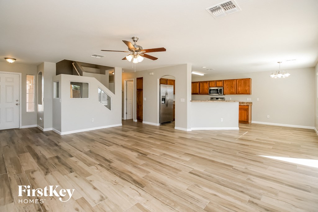 A spacious living room with wooden flooring and a ceiling fan.