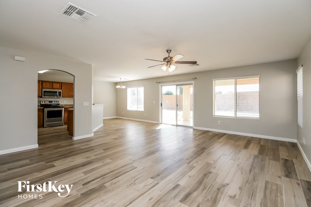A spacious living room with wooden flooring and a ceiling fan.