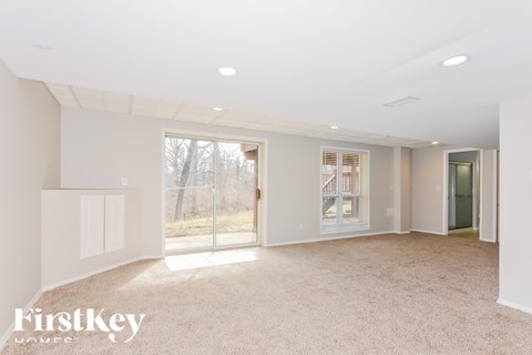 A spacious, empty room with a carpeted floor and white walls.