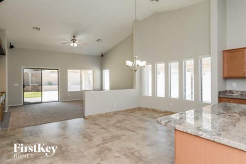 A spacious kitchen and living room with a marble countertop and a ceiling fan.