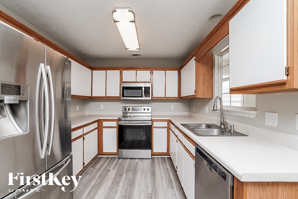 A kitchen with wooden cabinets and a stainless steel refrigerator.