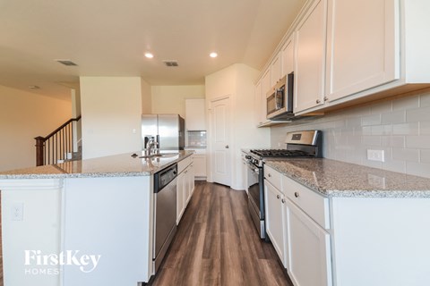 A kitchen with white cabinets and a stainless steel refrigerator.