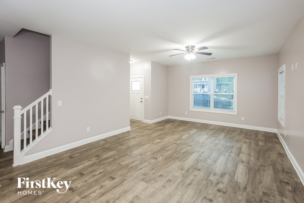 A spacious room with wooden flooring and a ceiling fan.