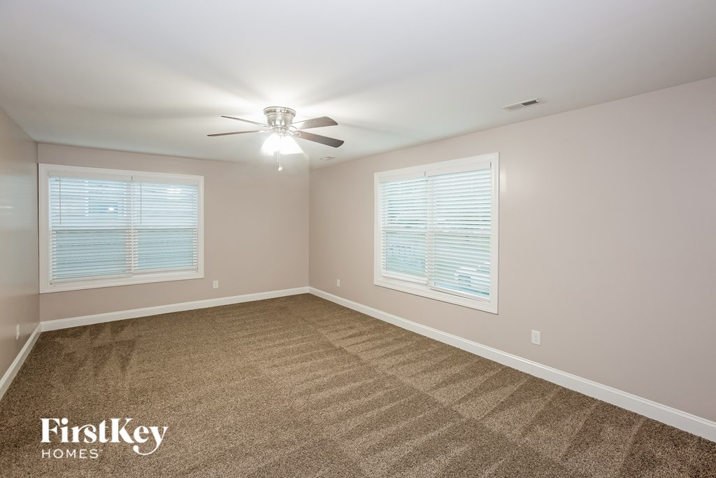 A room with a carpeted floor and a ceiling fan.
