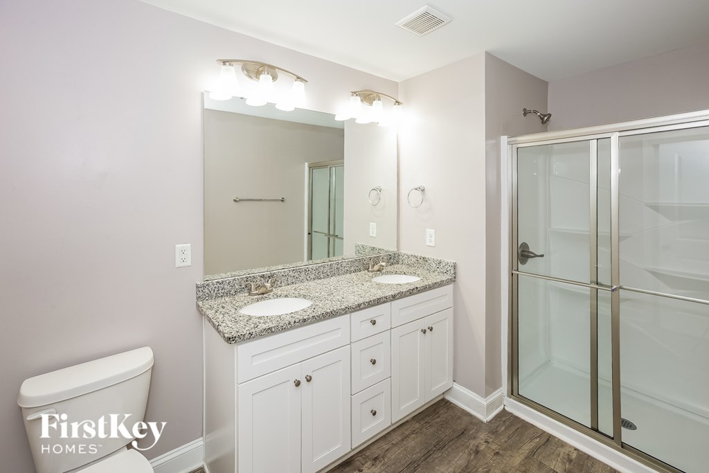 A bathroom with a granite countertop and a walk-in shower.