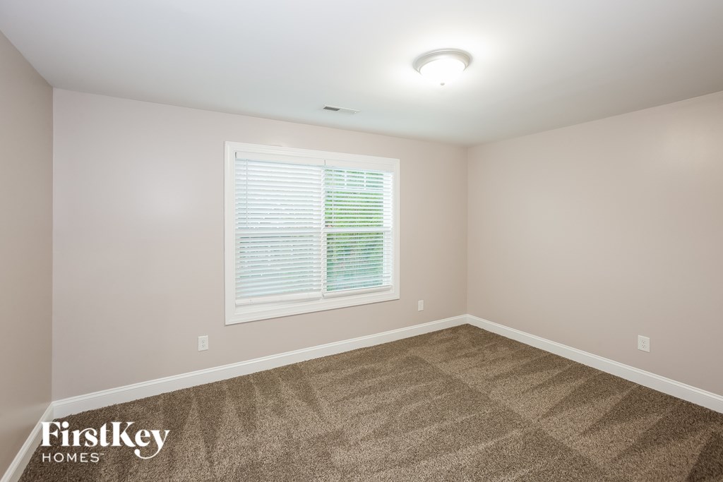 A room with a carpeted floor and a window with blinds.