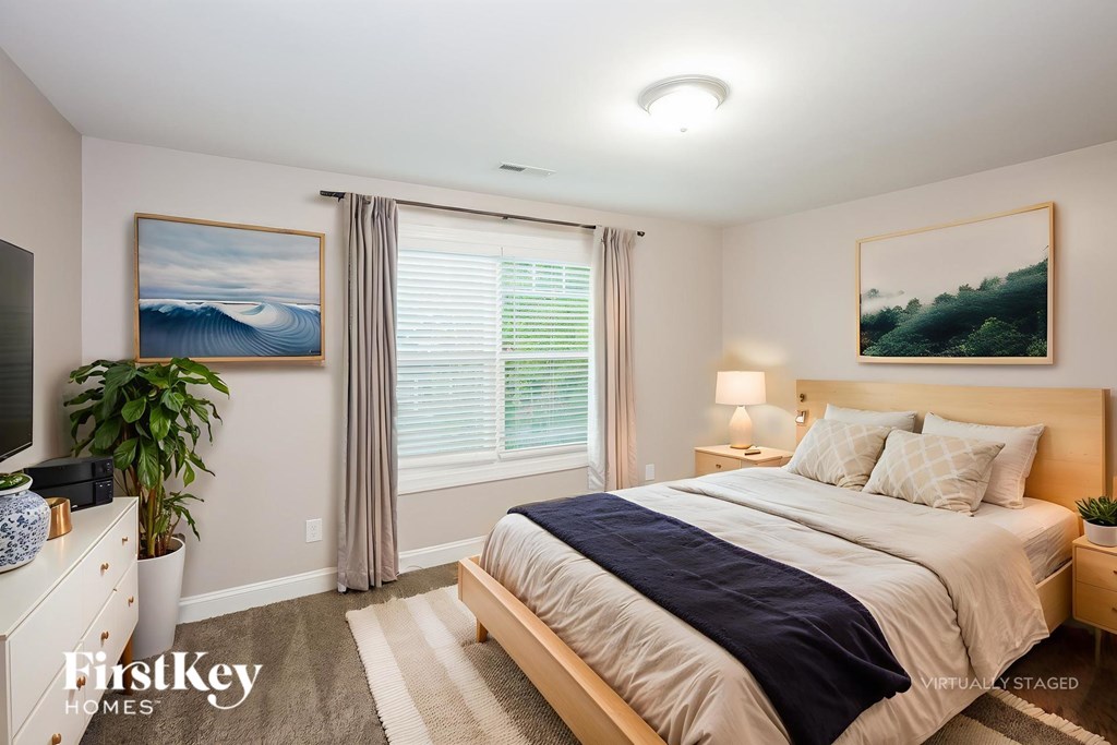 A bedroom with a bed, nightstand, and a painting on the wall.