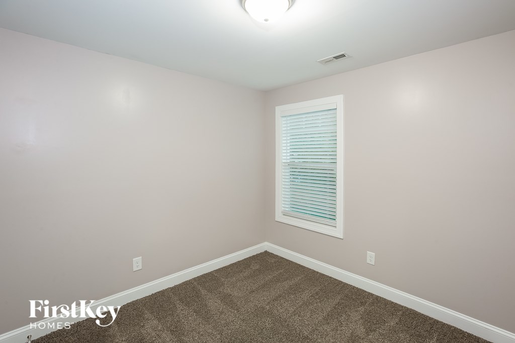 A room with a carpeted floor and a window with blinds.