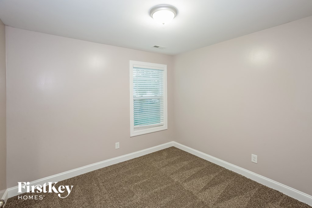 A room with a carpeted floor and a window with blinds.