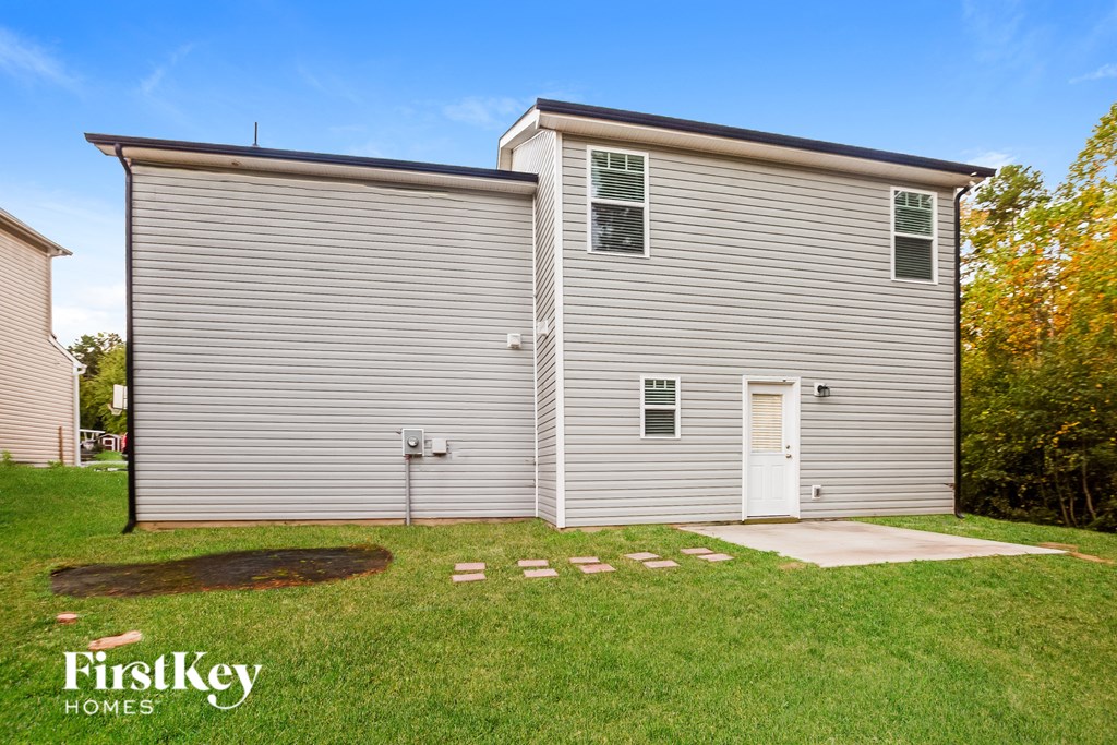 A grey house with a white door and a small yard.