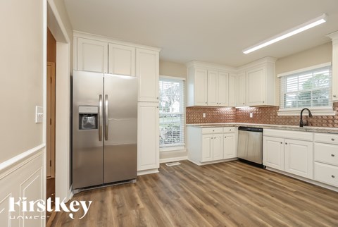 A kitchen with a stainless steel refrigerator and wooden floors.
