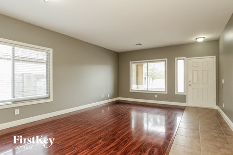 an empty living room with a hard wood floor and two windows