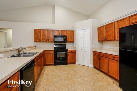 A kitchen with wooden cabinets and black appliances.