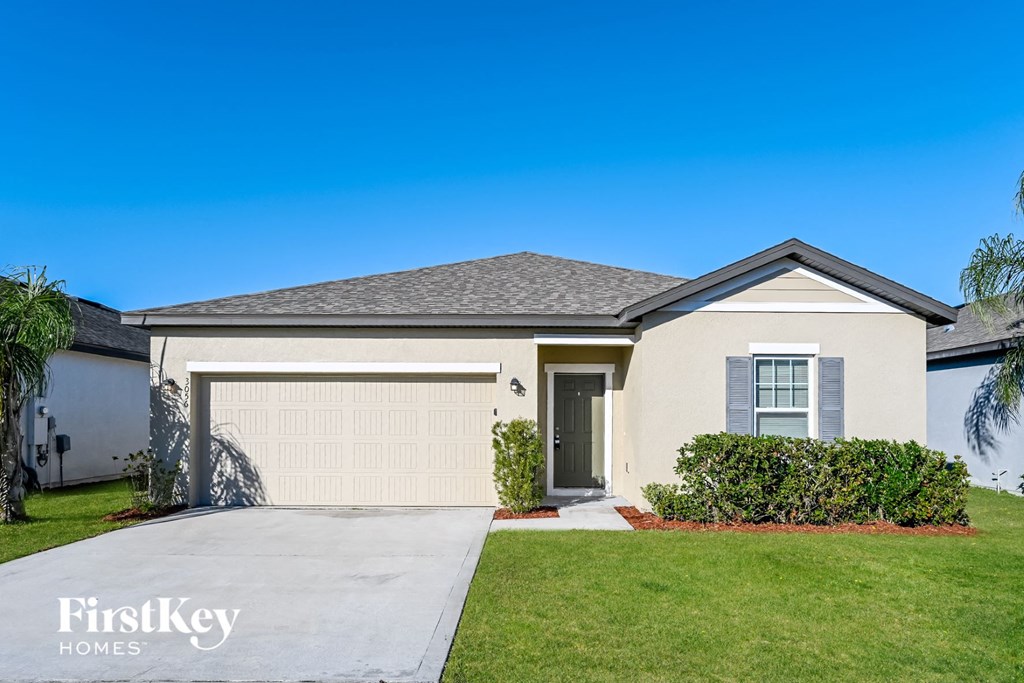 a beige house with a garage door and a lawn