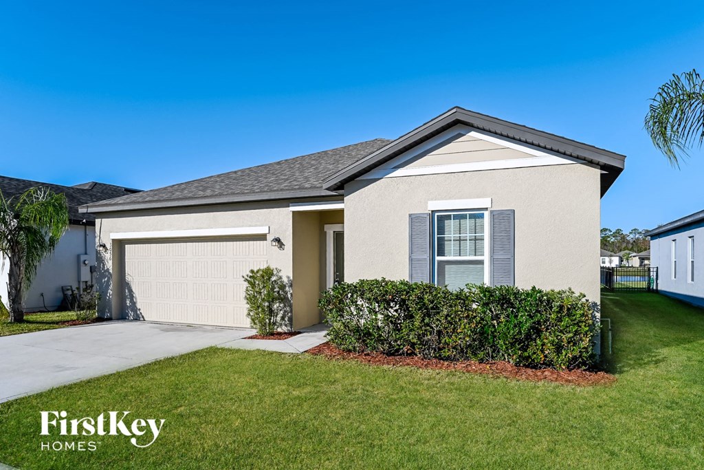 a beige house with a garage door and a lawn