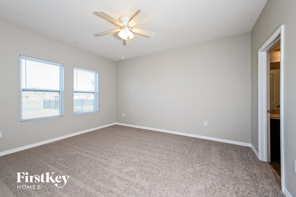 an empty living room with a ceiling fan and two windows