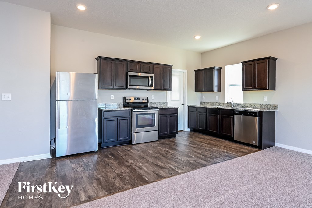 the kitchen has stainless steel appliances and dark wood cabinets