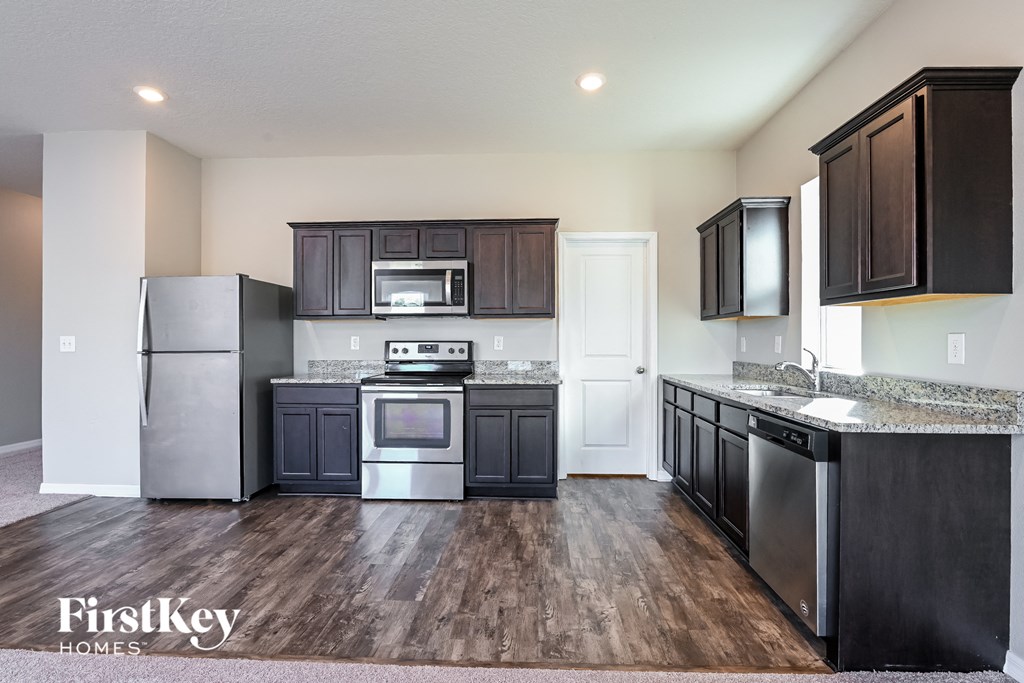 a kitchen with dark cabinets and stainless steel appliances