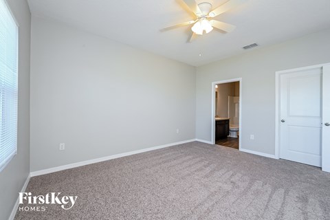 a spacious living room with white carpet and a ceiling fan