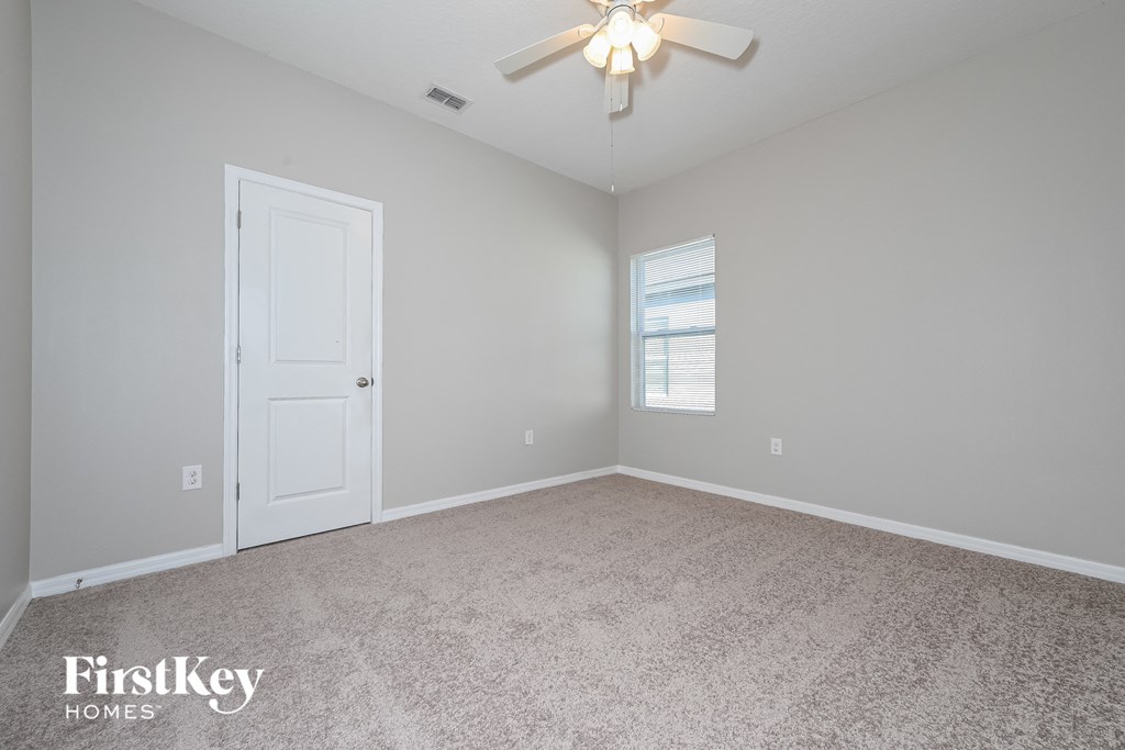 a bedroom with a ceiling fan and a white door