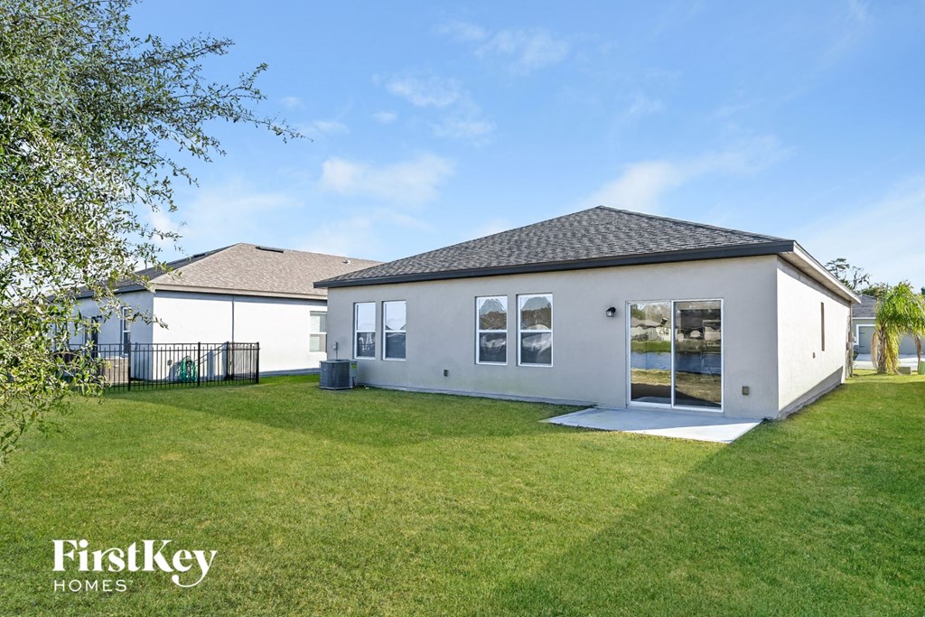 the exterior of a white house with a lawn and a backyard