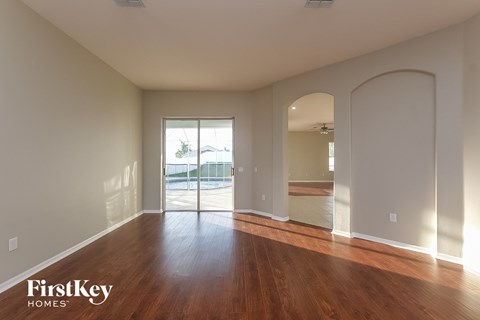 a living room with a hardwood floor and a door to a swimming pool