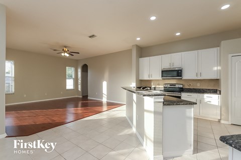 an open kitchen and living room with white cabinets and tile flooring