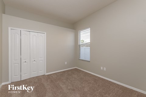 a bedroom with carpet and a window and two closets