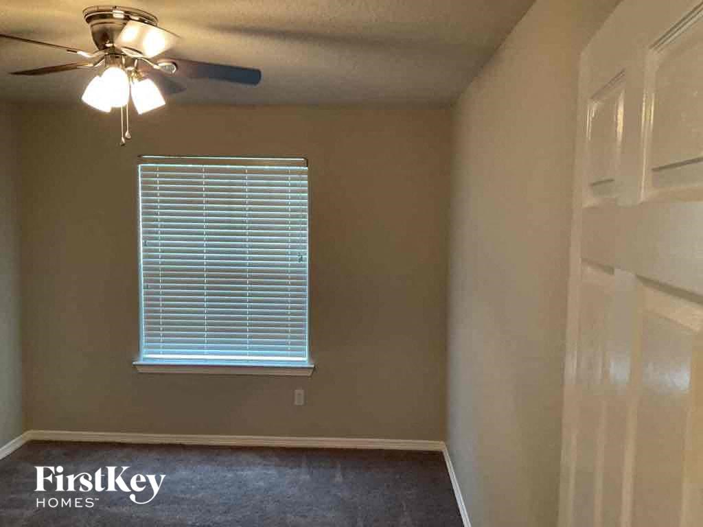 A room with a ceiling fan and a window with blinds.