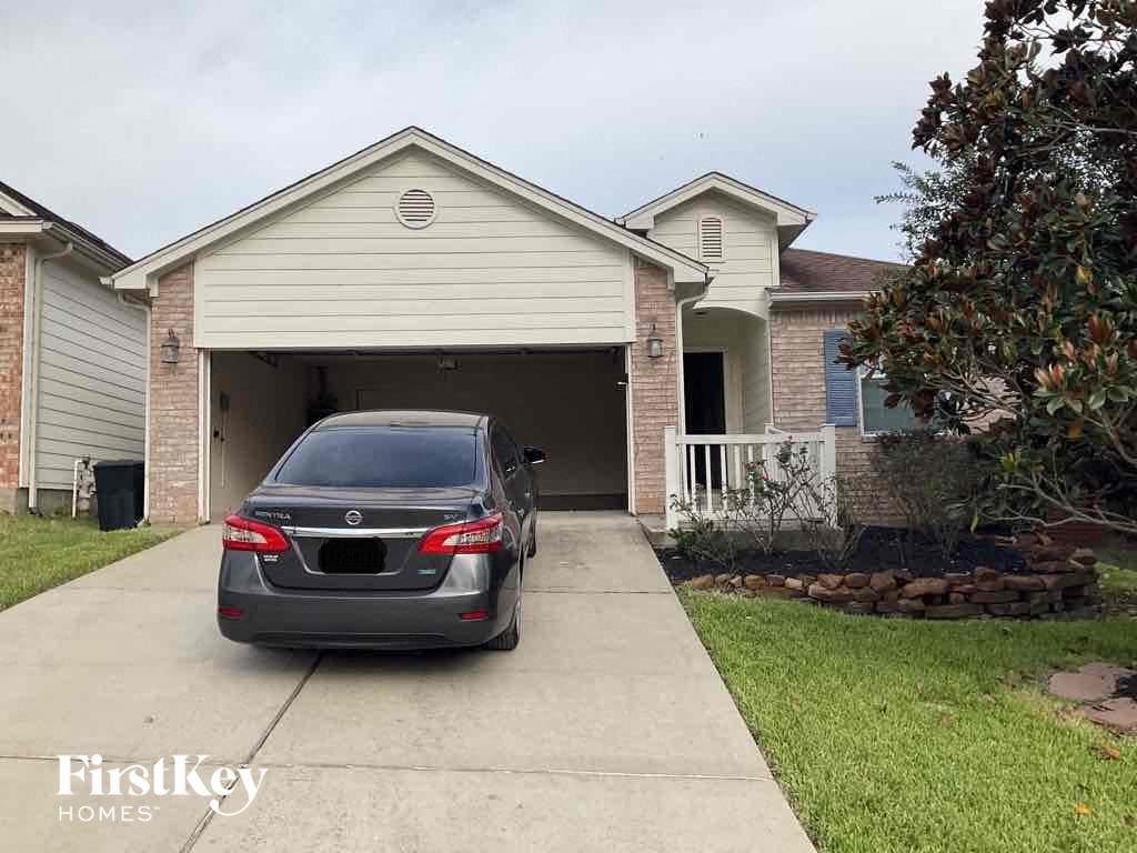 A car is parked in front of a house with a garage.