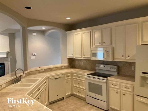 A kitchen with white cabinets and appliances, and a FirstKey Homes logo.