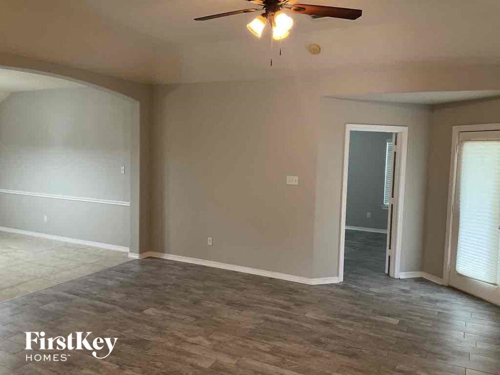 A spacious room with a ceiling fan and a door leading to another room.