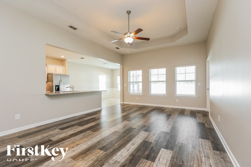 A spacious room with wooden flooring and a ceiling fan.