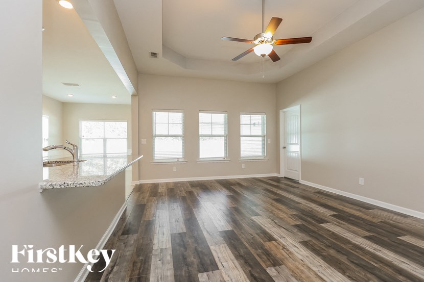 A spacious room with wooden flooring and a ceiling fan.