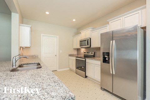 A kitchen with a refrigerator, sink, and microwave.
