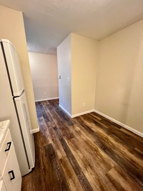 A kitchen with a white refrigerator and wooden floors.